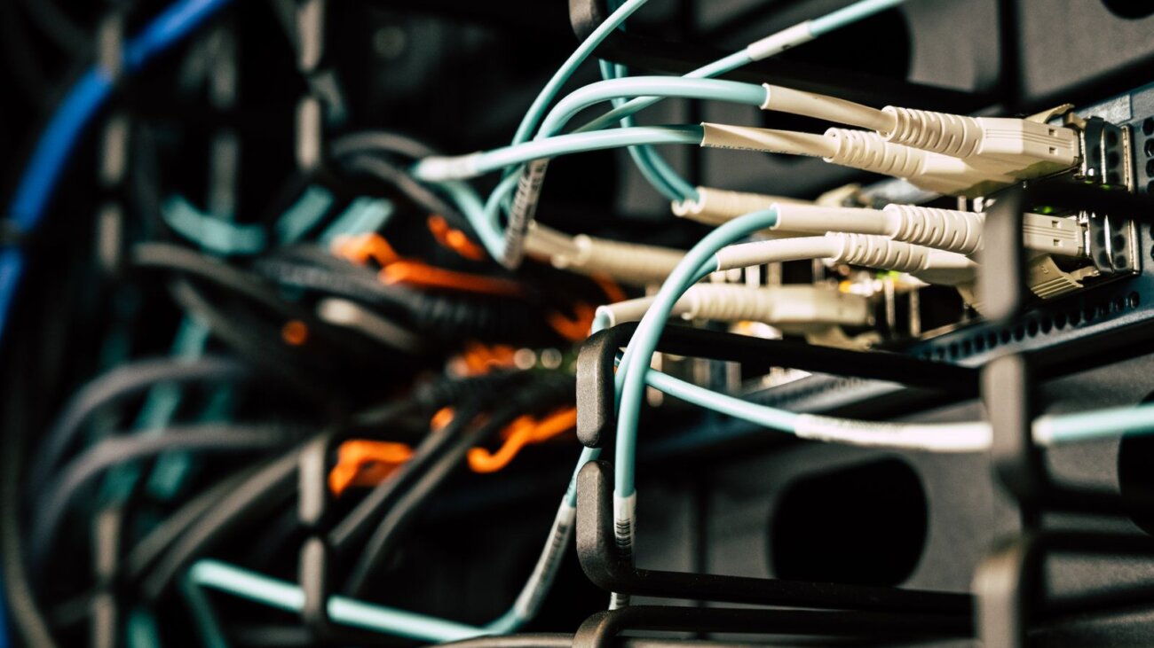 Tangled wires connected to servers in a server room, a visual metaphor for technical debt